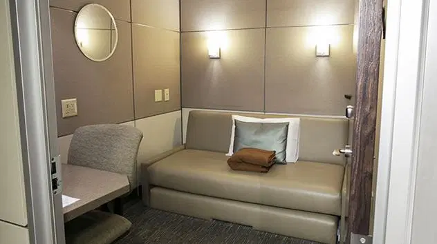 Mini quarto Minute Suites no Terminal 8 do Aeroporto JFK em Nova York, espaço privativo para descanso e trabalho disponível via Priority Pass.