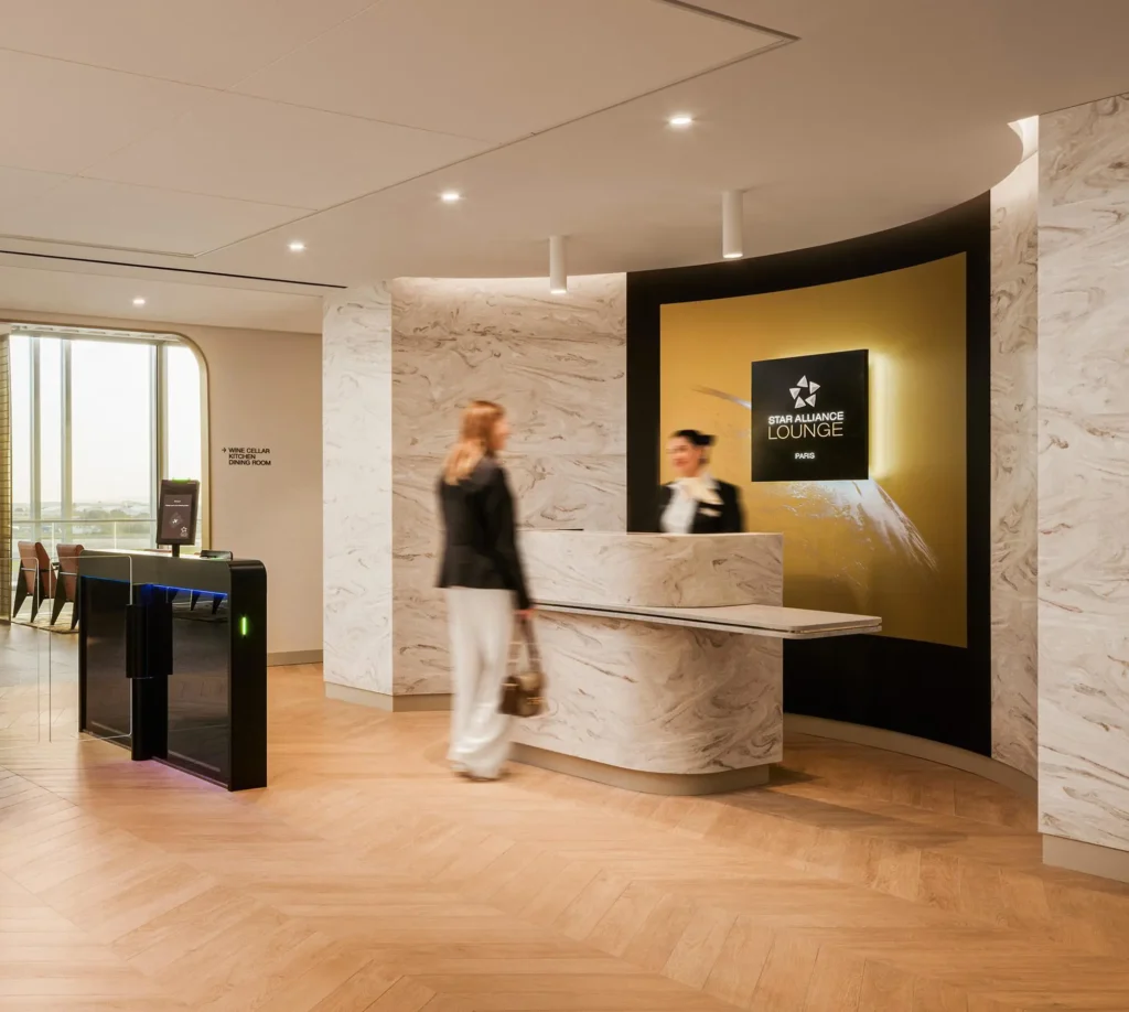 Recepção da sala VIP Star Alliance Lounge Paris, com balcão de mármore, iluminação sofisticada e controle de acesso no Aeroporto Charles de Gaulle (CDG), em Paris.