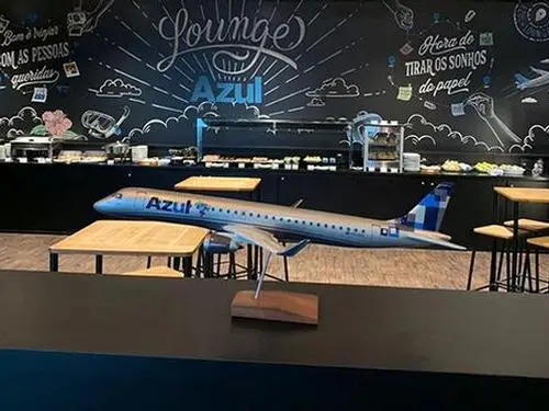 Interior do Lounge Azul no Aeroporto Internacional de Viracopos (VCP), em Campinas, com área de alimentação, mesas para descanso e decoração temática da Azul Linhas Aéreas.