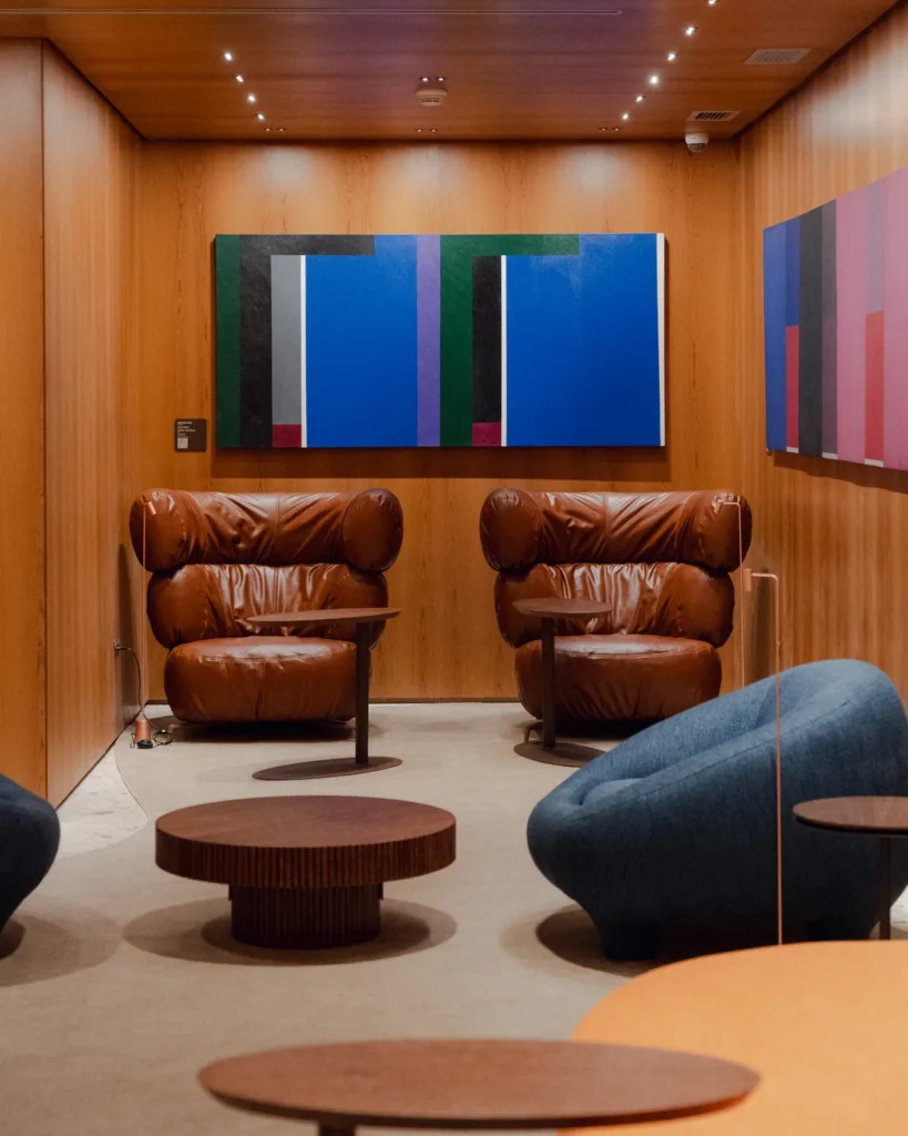 Área de descanso da Sala VIP Pedra Preta do Itaú Personnalité no Terminal 3 de Guarulhos, com poltronas premium, obras de arte e ambiente exclusivo.